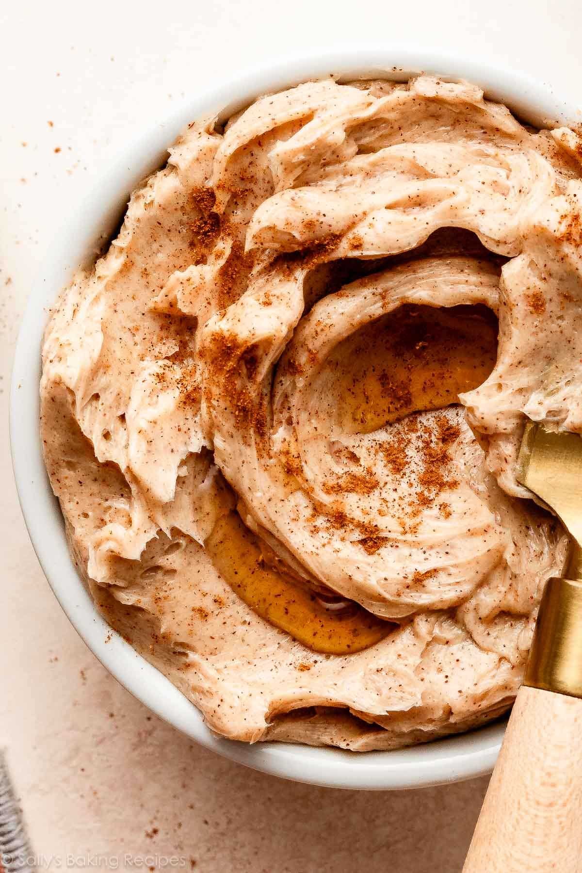 gros plan du beurre de cannelle dans un plat blanc avec un filet de sirop d'érable sur le dessus.