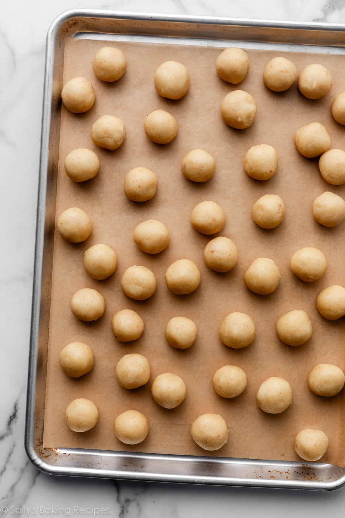 boules de gâteau sur une plaque à pâtisserie recouverte de papier sulfurisé.