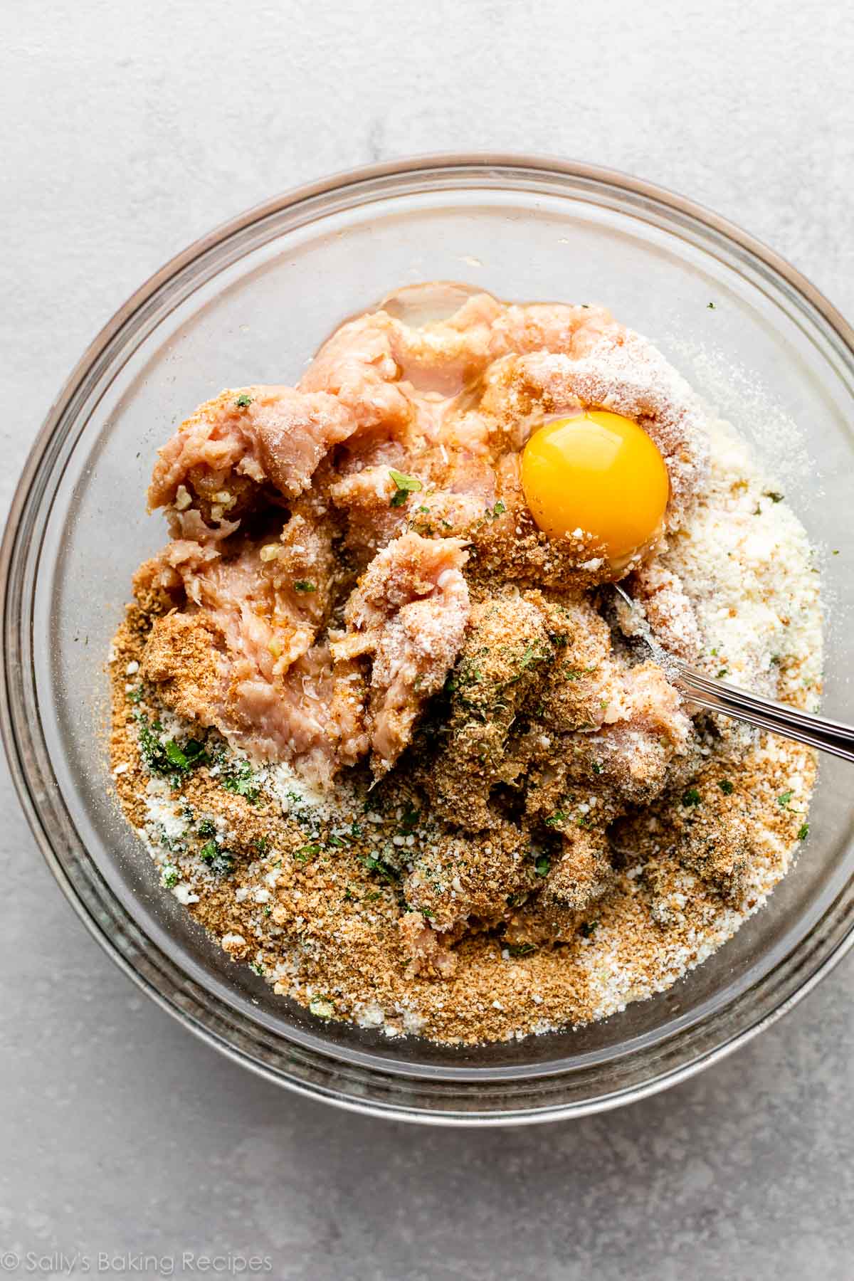 ingrédients de la mixture de boulettes dans un bol en verre avec une cuillère prête à mélanger.