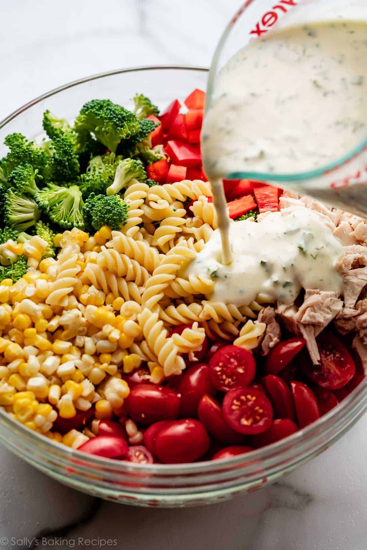 versez la vinaigrette crémeuse sur un bol de pâtes, tomates, maïs et brocoli