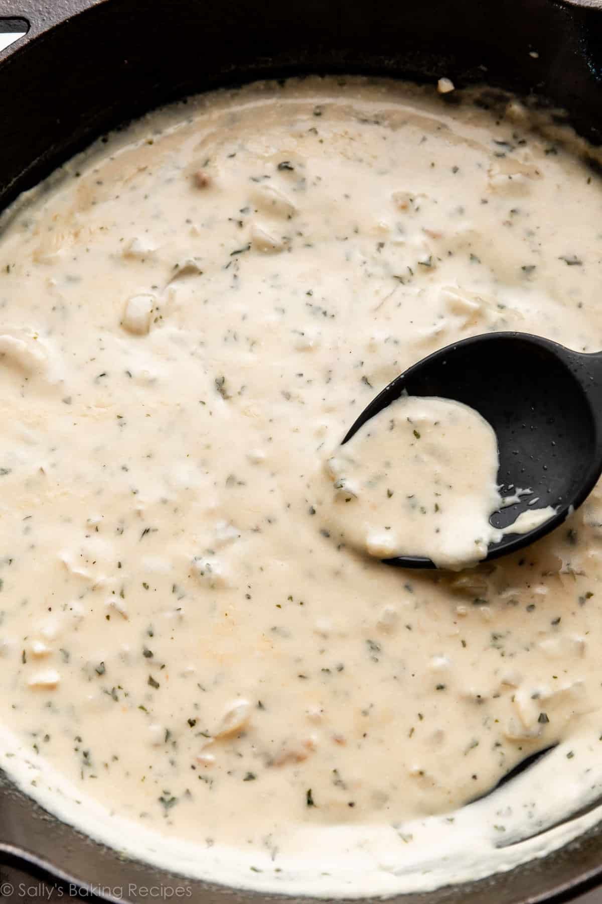 sauce crémeuse à l'ail avec du persil dans une poêle en fonte.