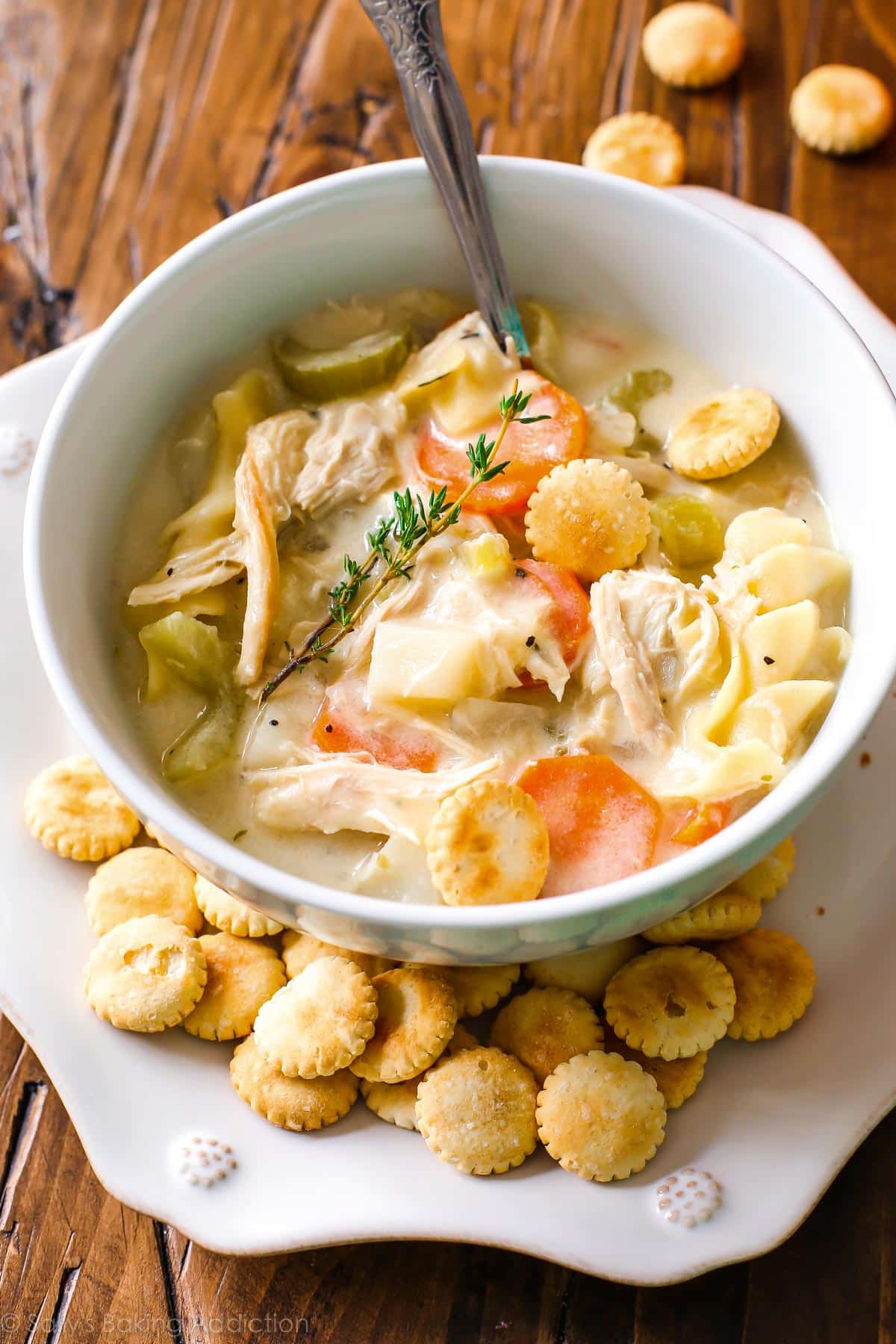 Soupe crémeuse aux nouilles de poulet dans un bol blanc avec des crackers.