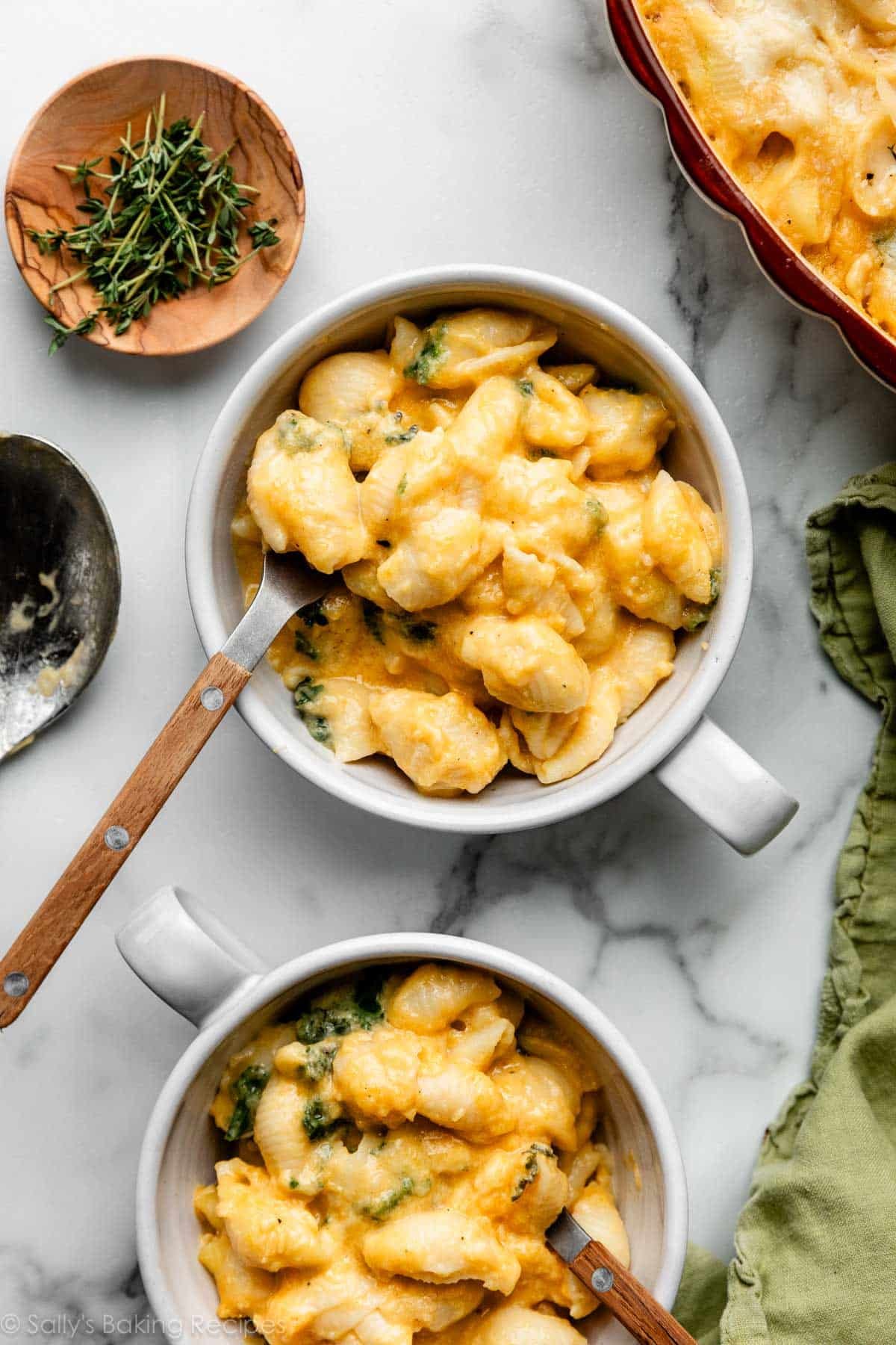 deux bols de macaroni au fromage à la courge butternut avec des fourchettes en bois et en métal dedans.