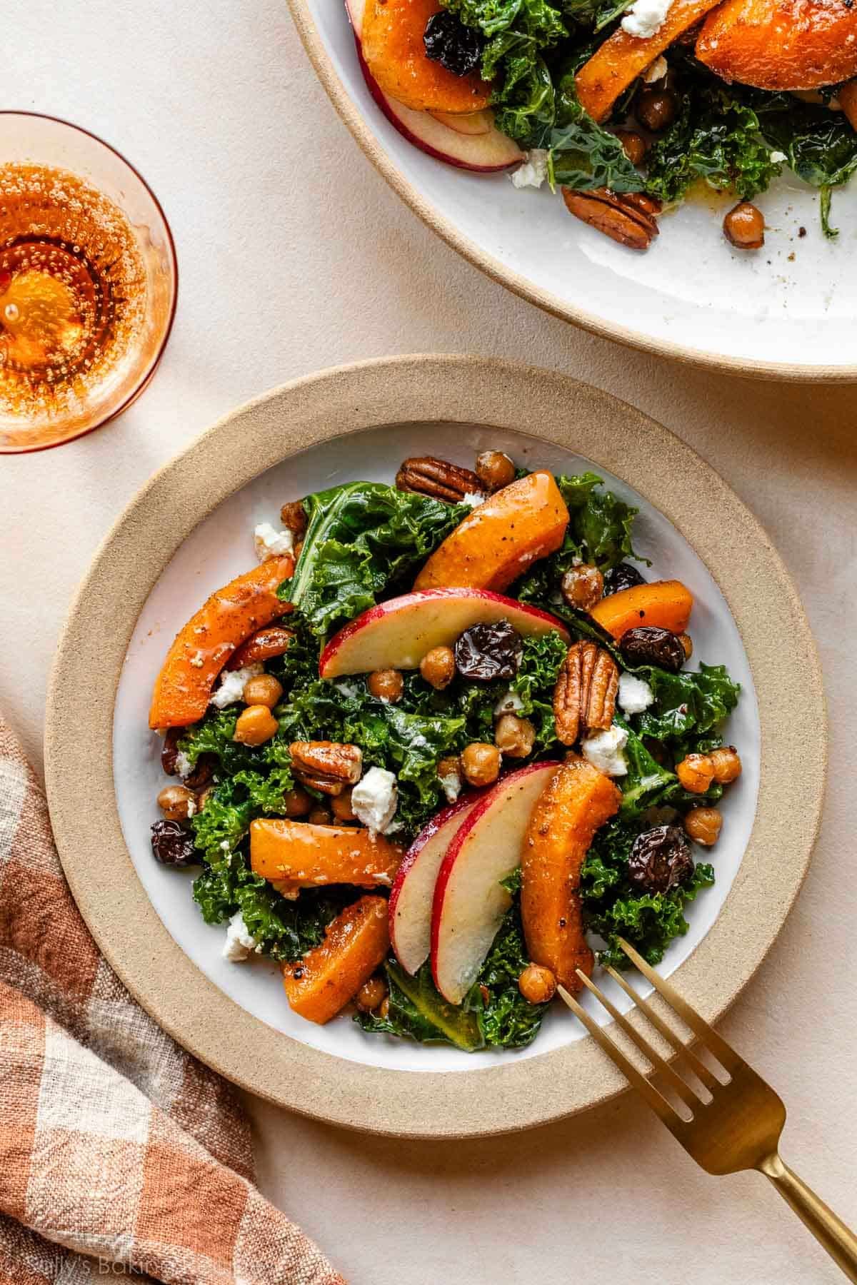 salade d'automne au kale et courge butternut sur une petite assiette avec du lin orange à carreaux à côté.