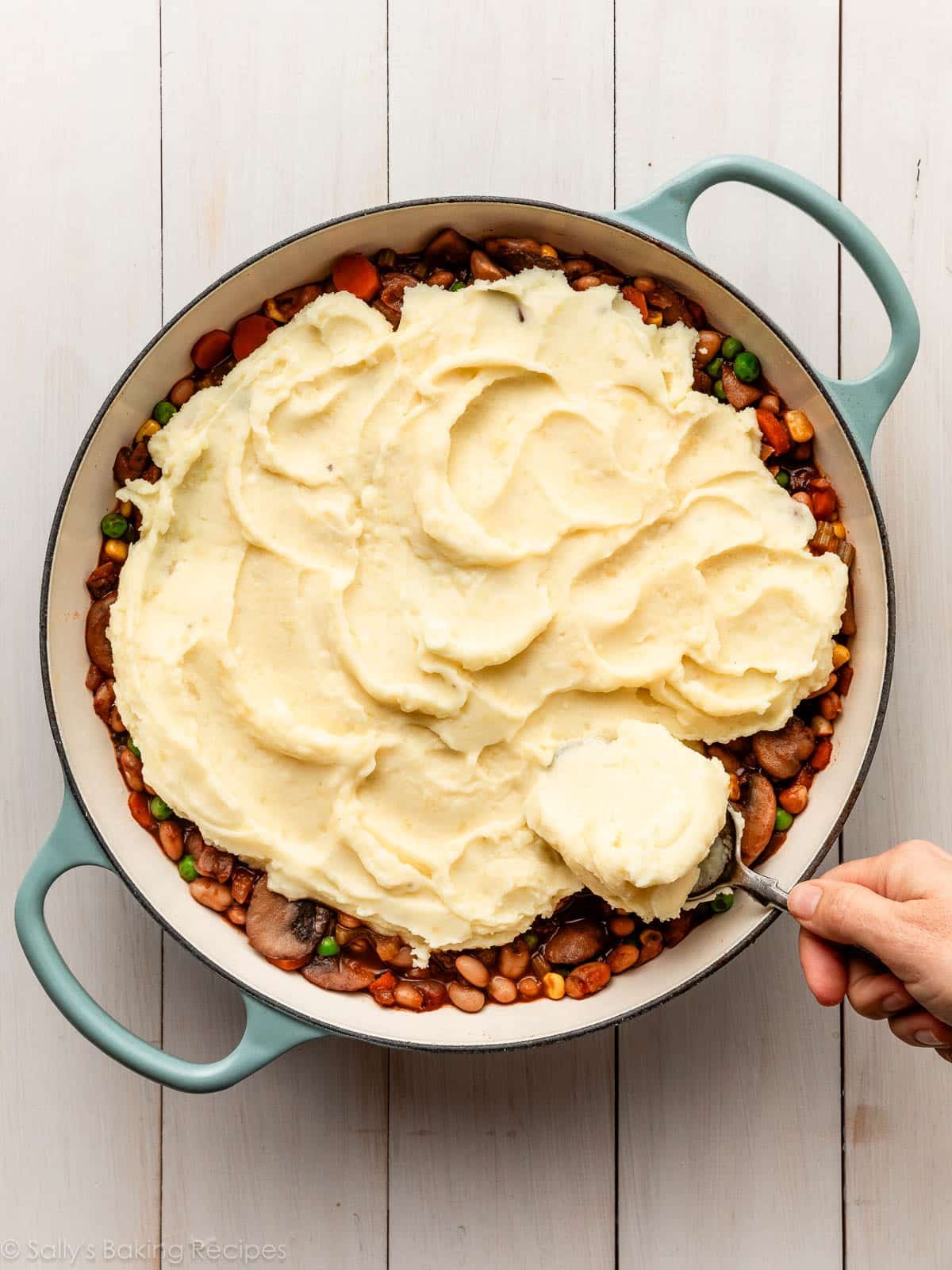 étalement de purée de pommes de terre sur le mélange de haricots et de légumes.