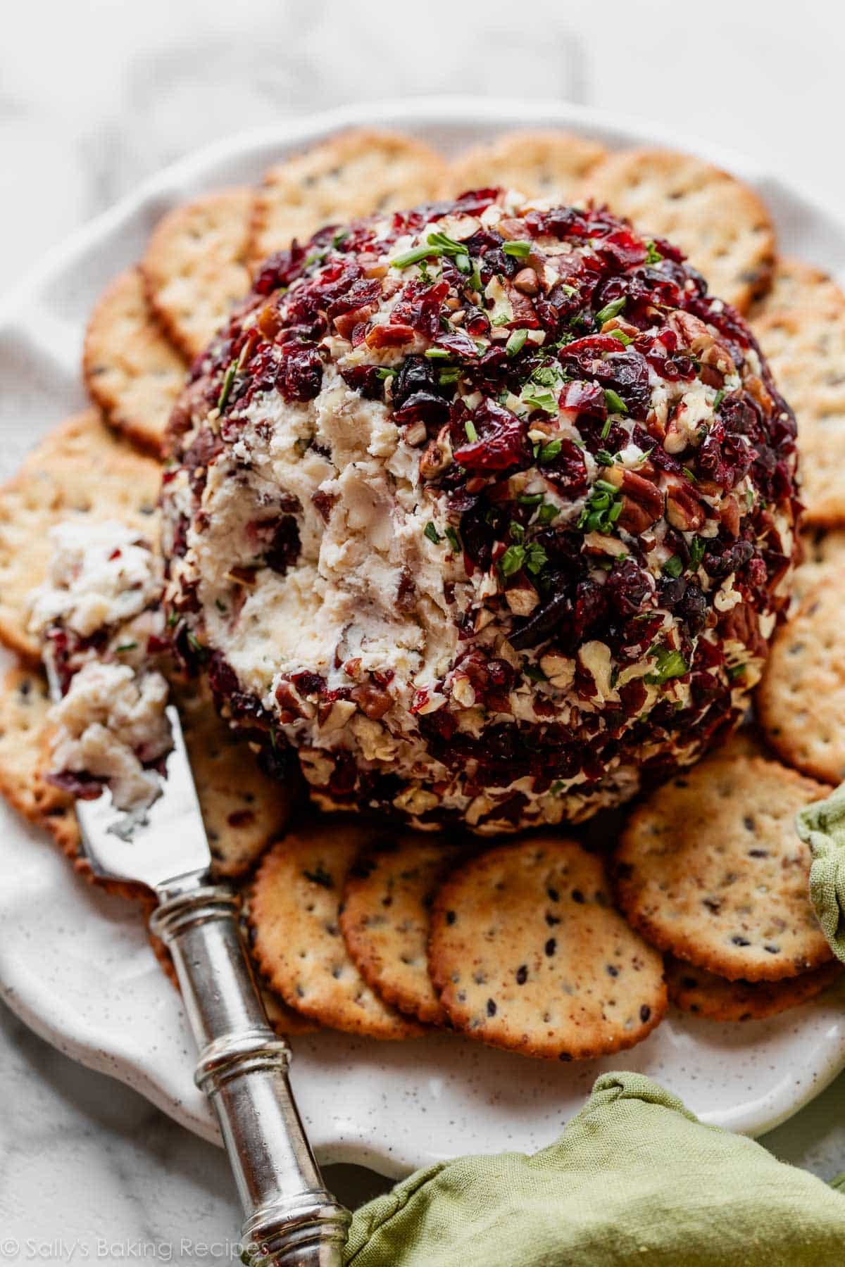 boule de fromage aux canneberges et cheddar blanc, coupée et servie avec des crackers.