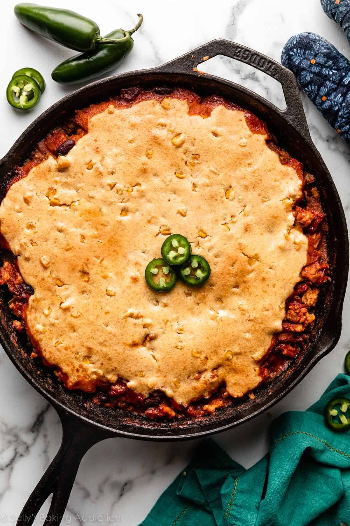 chili dans une poêle en fonte noire garni de pain de maïs et de jalapeños tranchés.