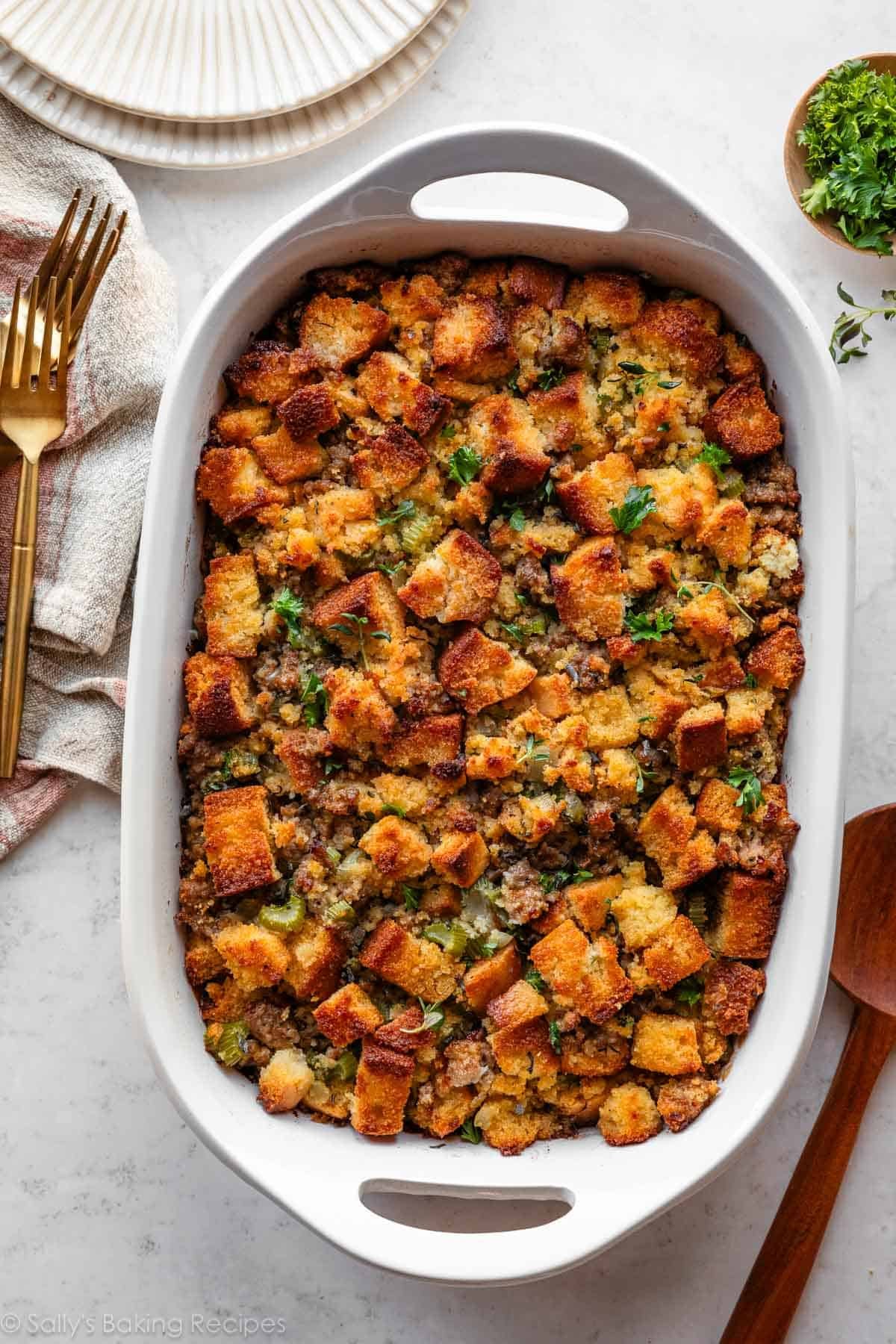 farce au pain de maïs avec saucisse et herbes dans un plat en casserole blanc.