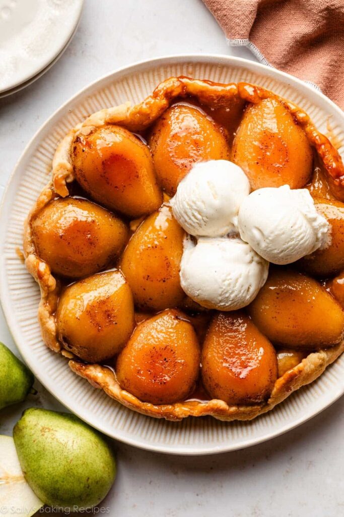 pear tarte tatin on a serving plate with 3 scoops of vanilla ice cream.