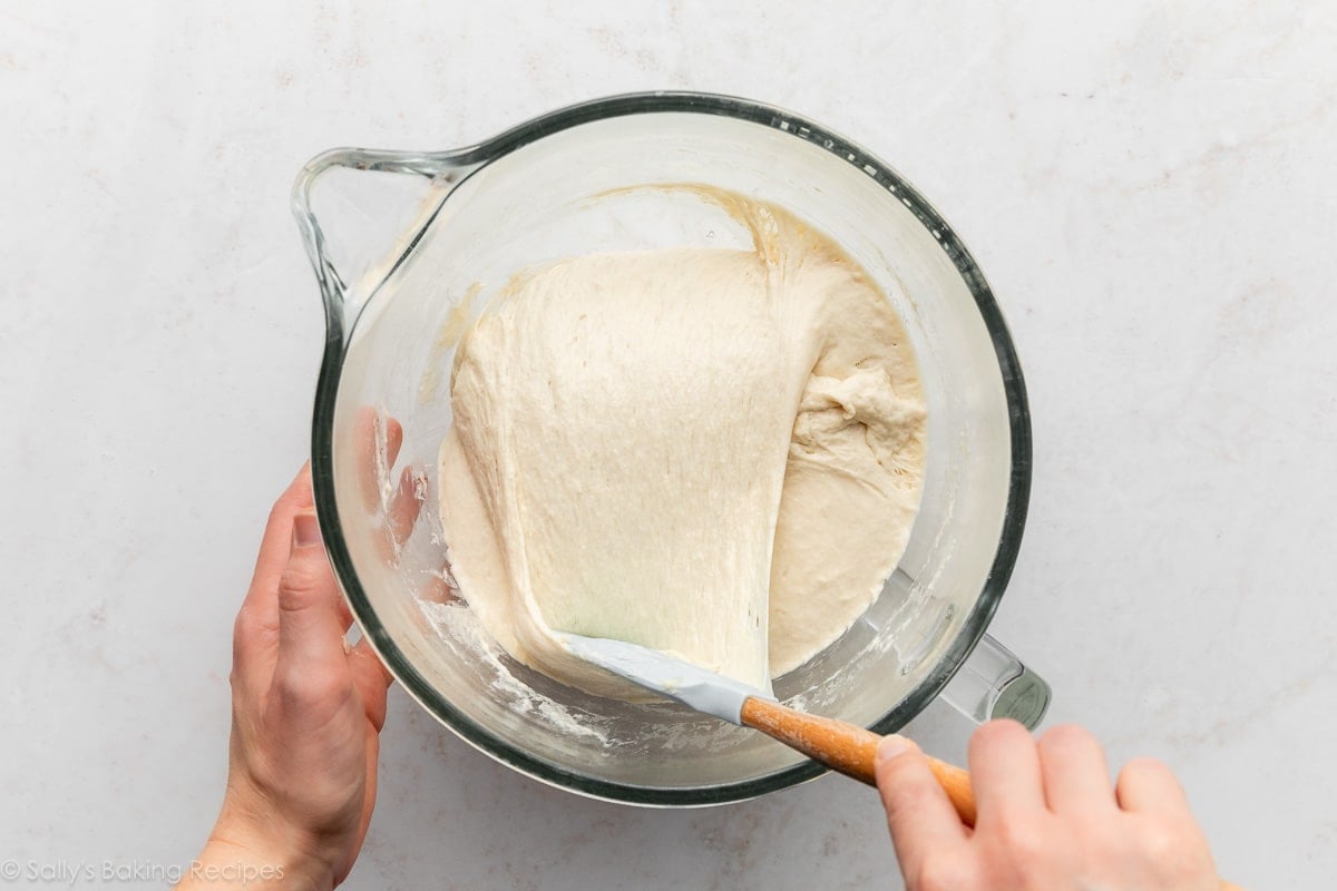 spatule tirant la pâte sur elle-même dans un bol en verre.