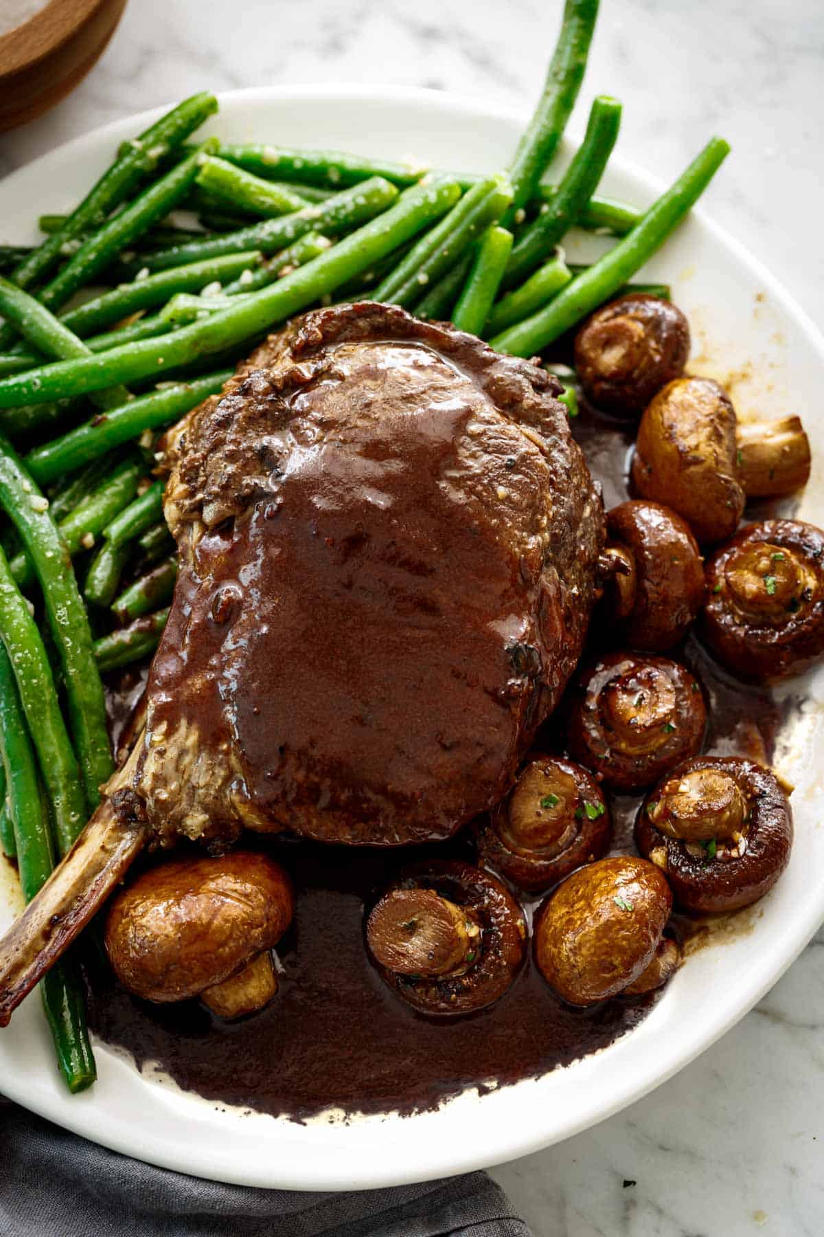 Profitez des Haricots Verts Sautés au Beurre servis en accompagnement d'un juteux rôti de côtes et de champignons rôtis à la sauce soja balsamique.