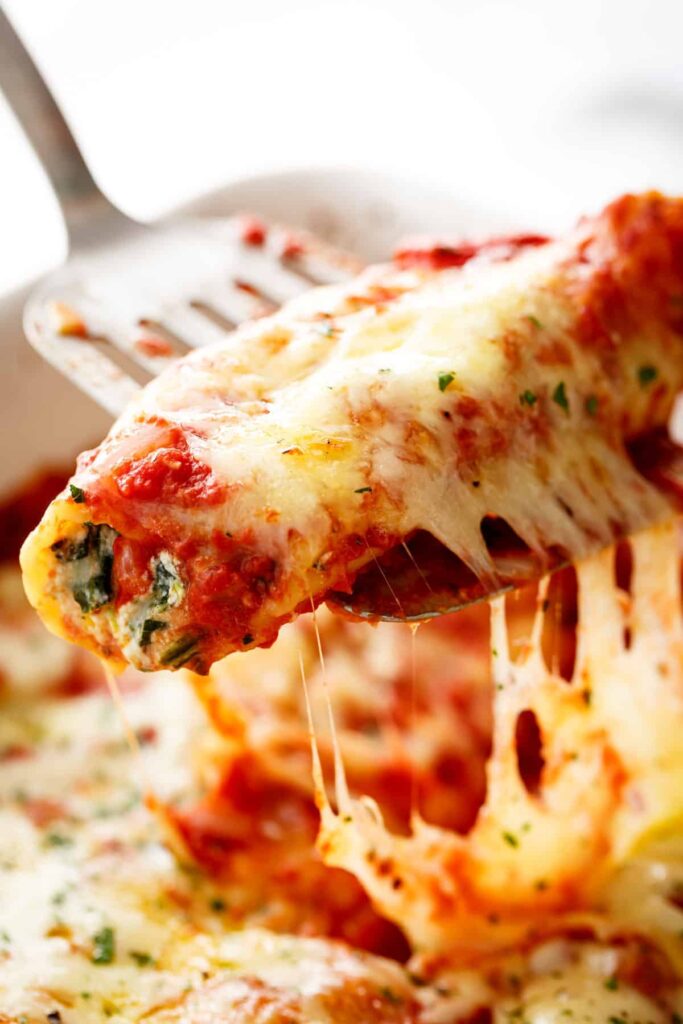 A spatula holding Spinach Cheese Manicotti