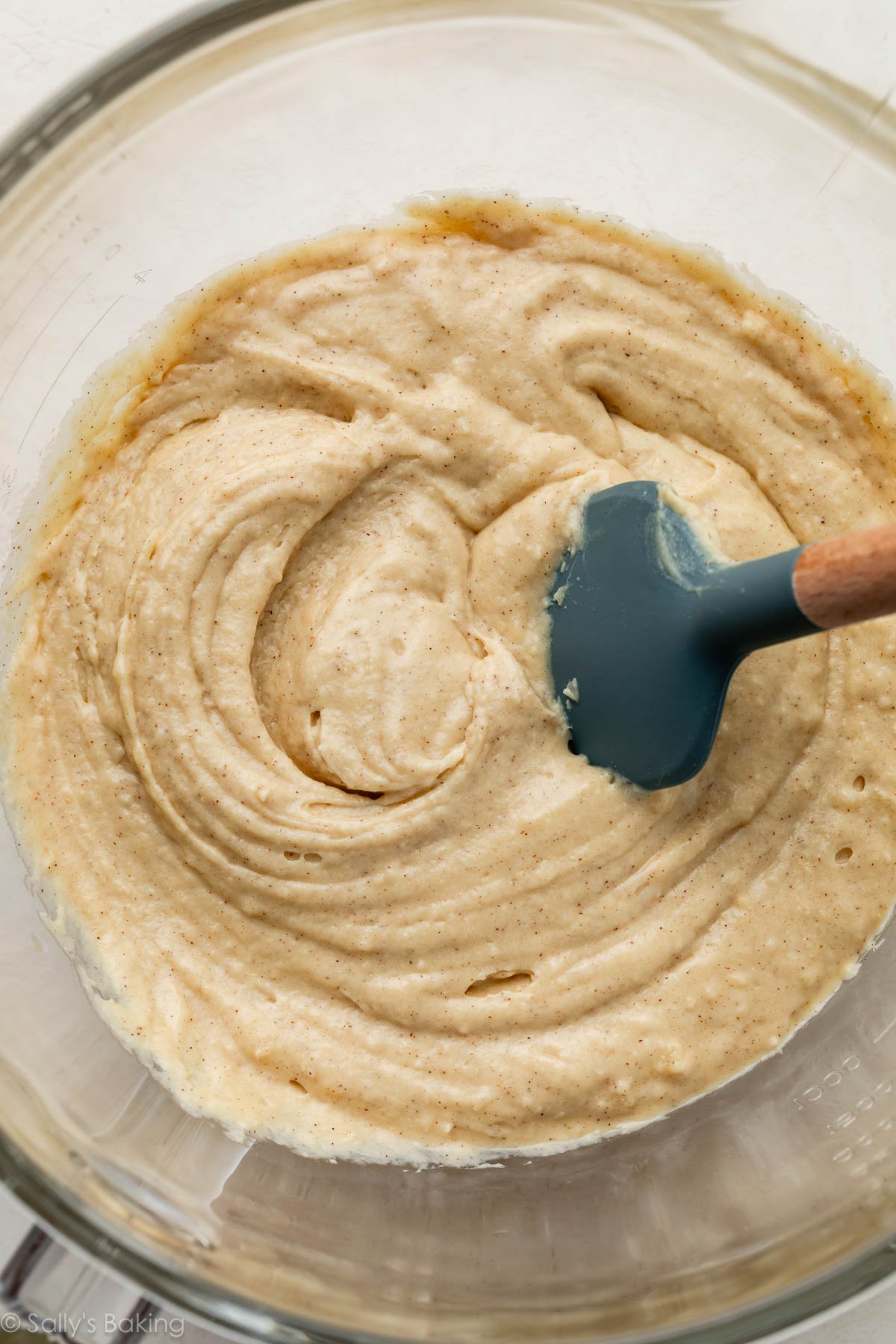 pâte dans un bol en verre avec spatule bleue.