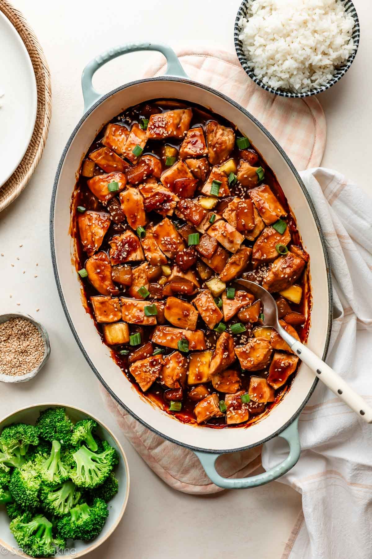 poulet teriyaki à l'ananas cuit au four dans un plat de cuisson oval avec un bol de riz blanc et du brocoli autour.