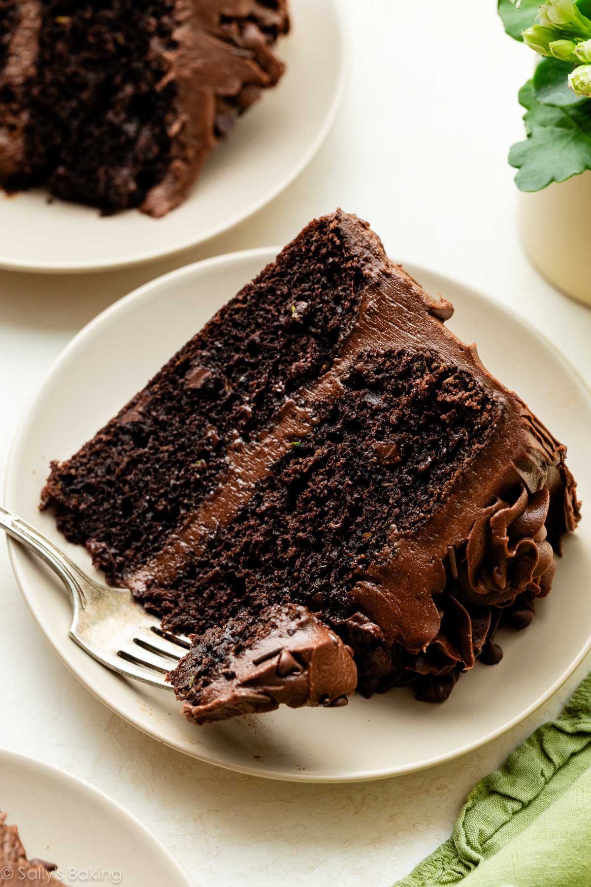 part de gâteau au chocolat et courgette avec glaçage au chocolat sur une assiette beige.