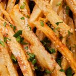 close up photo of crispy fries with salt and chopped parsley