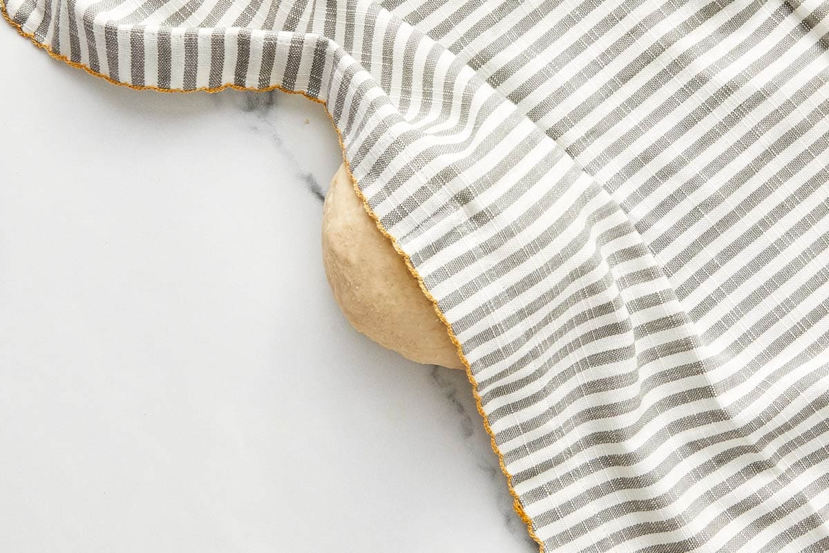 Pâte à bao reposant sous une serviette à rayures lors de la fermentation.