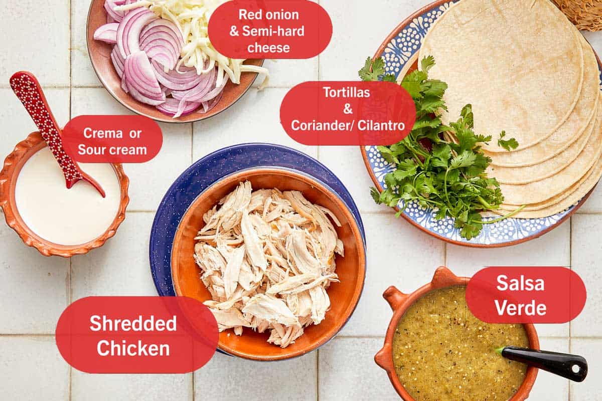Bols d'ingrédients pour enchiladas, y compris des tortillas, du fromage et diverses épices, disposés sur un comptoir de cuisine.