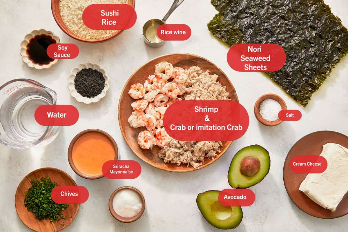 Ingrédients pour la casserole de sushi disposés sur une table, mettant en avant le riz, les algues, le poisson et des légumes colorés.