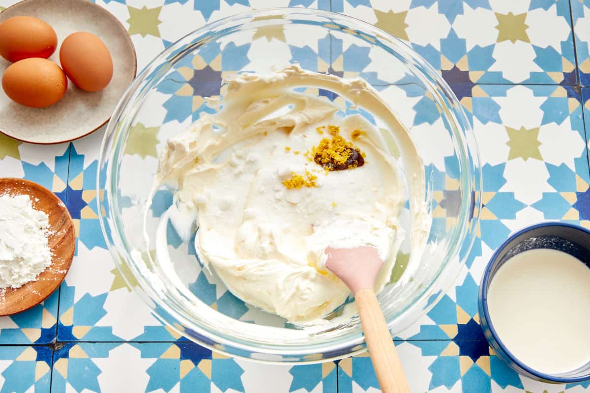 Sucre, vanille et zeste de citron ajoutés au mélange de fromage à la crème dans un bol