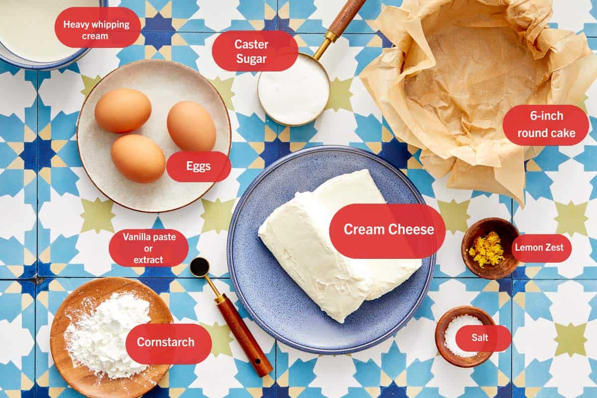 Ingrédients pour le cheesecake Basque disposés sur une surface à motifs avec étiquettes