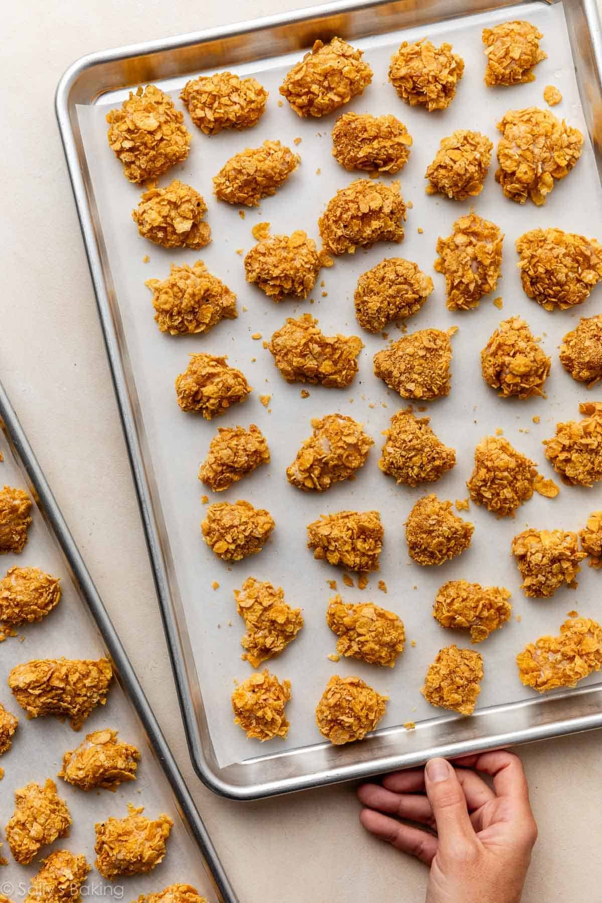 main prenant un plateau de morceaux de poulet enrobés.