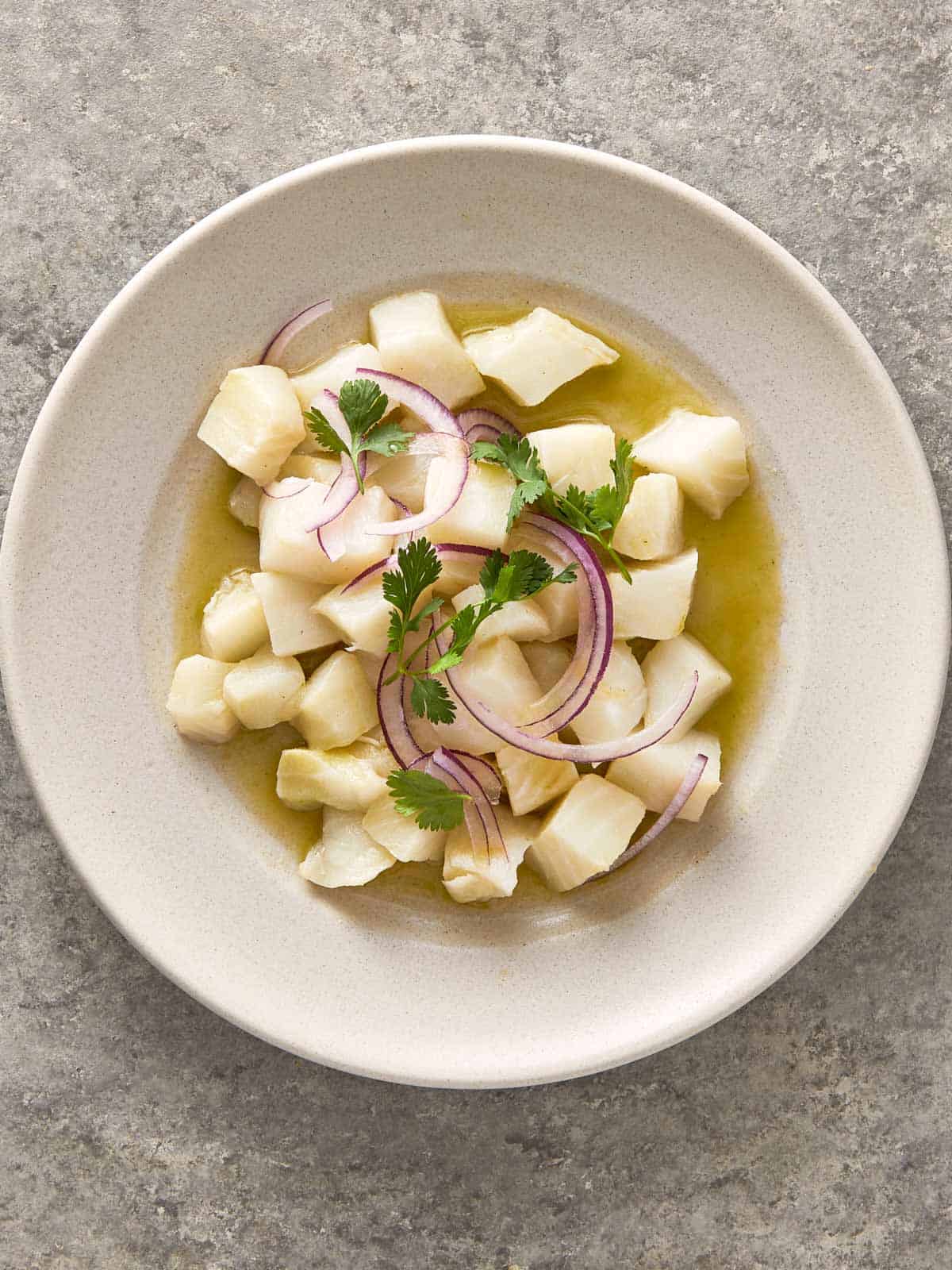 Ceviche de poisson frais avec des cubes de poisson blanc tendre, garnis d'oignon rouge et de coriandre.