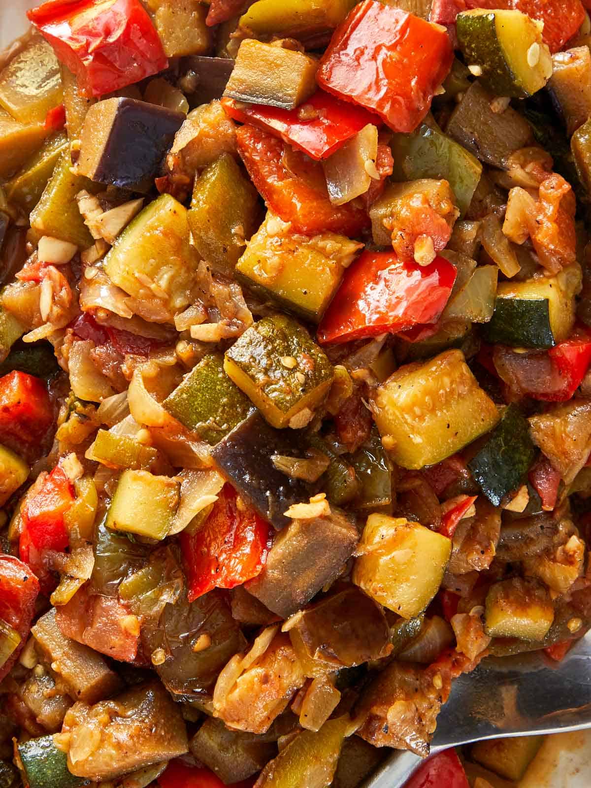 Un bol vibrant de ratatouille, rempli de légumes cuits assortis, accompagné d'une cuillère pour servir.