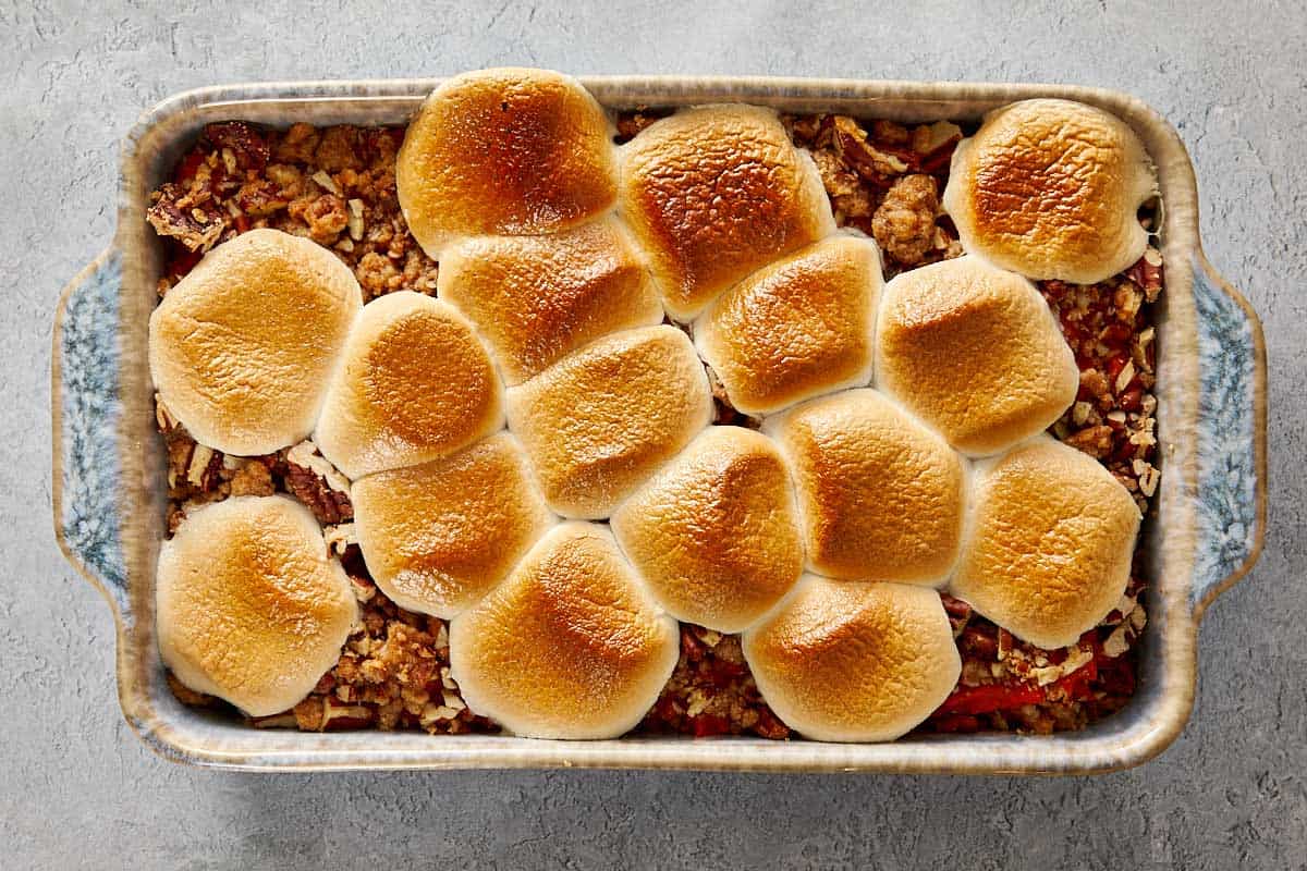 Casserole de patates douces dans un plat de cuisson, recouverte de guimauves dorées grillées uniformément.